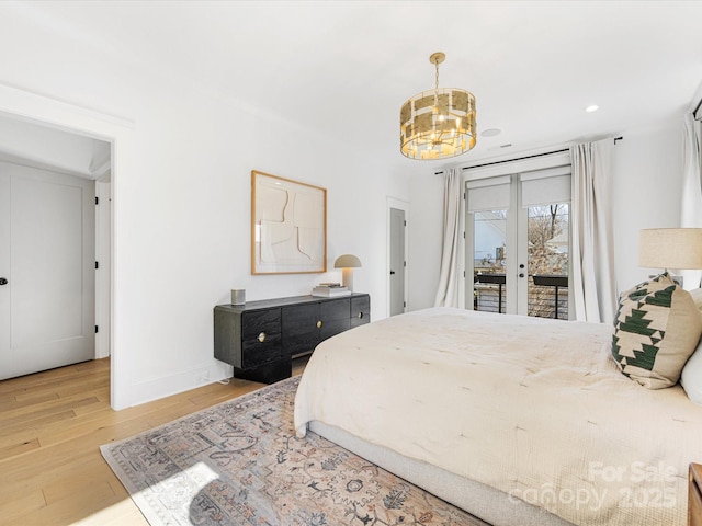 bedroom with access to exterior, a notable chandelier, light hardwood / wood-style floors, and french doors