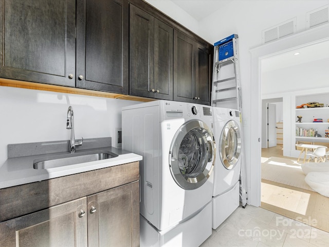 laundry area with light tile patterned flooring, cabinets, sink, and washing machine and dryer