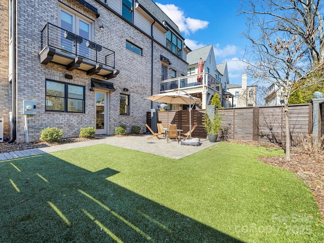 back of house featuring a balcony, a patio area, and a lawn