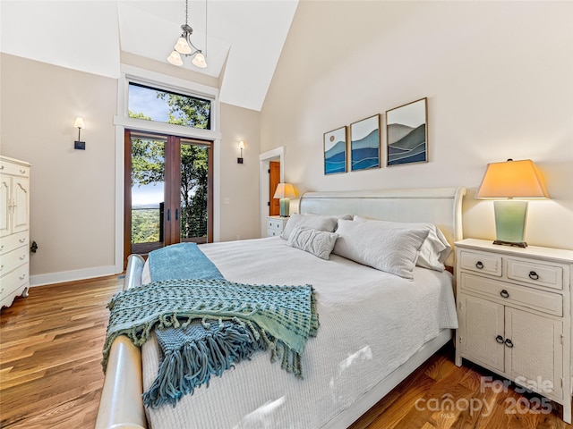 bedroom featuring baseboards, wood finished floors, access to exterior, french doors, and high vaulted ceiling