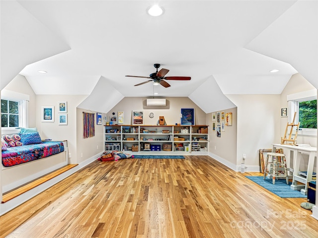 interior space featuring lofted ceiling, an AC wall unit, wood finished floors, and baseboards