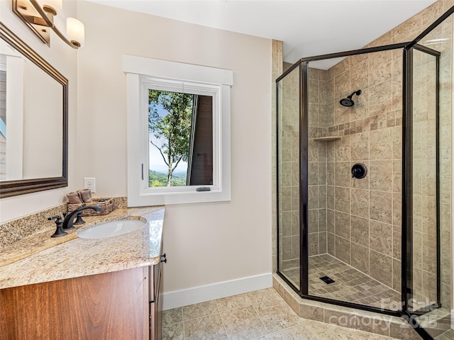 bathroom featuring tile patterned flooring, baseboards, a shower stall, and vanity