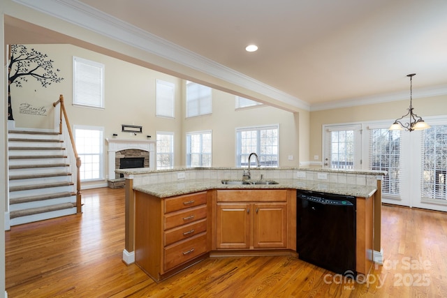 kitchen featuring dishwasher, sink, light stone counters, and decorative light fixtures