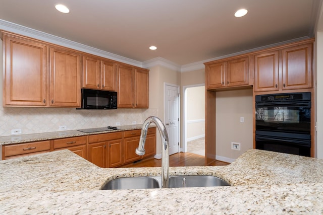 kitchen featuring tasteful backsplash, sink, light stone counters, black appliances, and crown molding