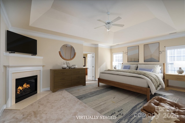 bedroom featuring multiple windows, crown molding, and a tray ceiling