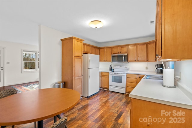 kitchen featuring dark wood-type flooring, sink, and white appliances