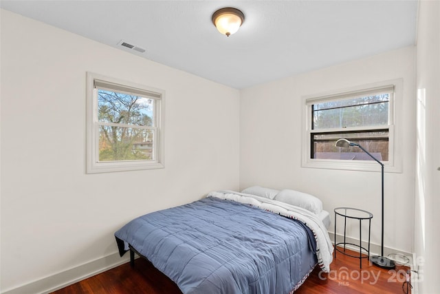 bedroom featuring dark wood-type flooring and multiple windows