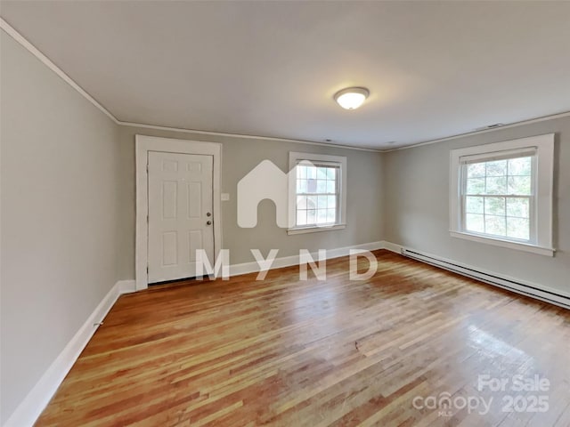 empty room with ornamental molding, light hardwood / wood-style flooring, and a baseboard heating unit