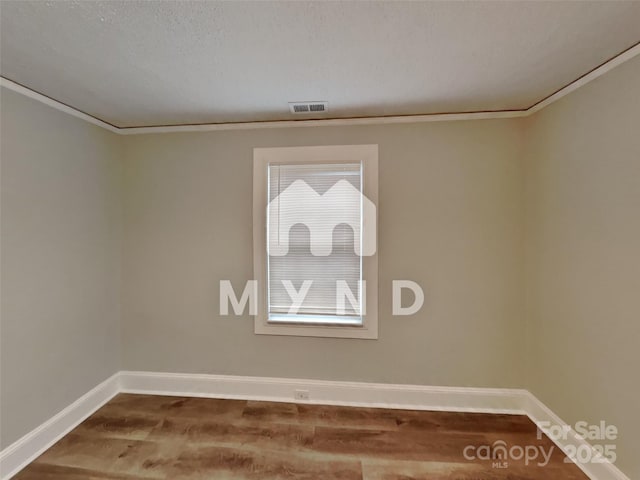 unfurnished room featuring wood-type flooring, ornamental molding, and a textured ceiling