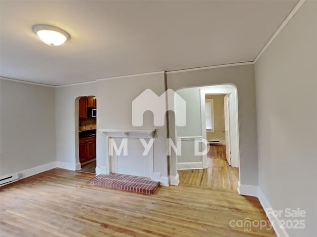 interior space with crown molding, light wood-type flooring, and a baseboard heating unit