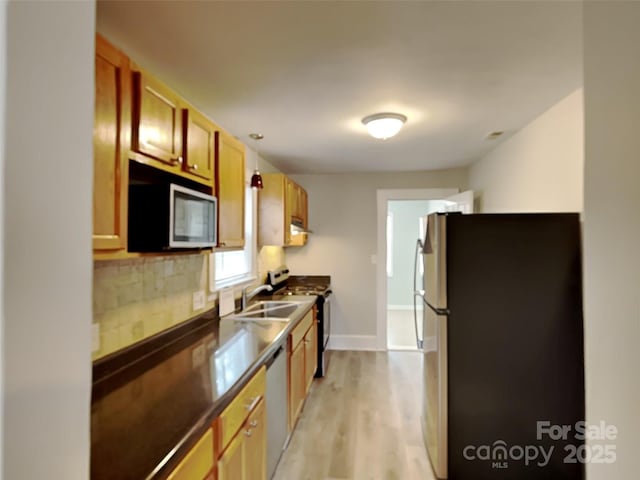 kitchen featuring light wood-type flooring, appliances with stainless steel finishes, sink, and backsplash