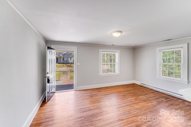 spare room with a wealth of natural light, a baseboard heating unit, baseboards, and wood finished floors