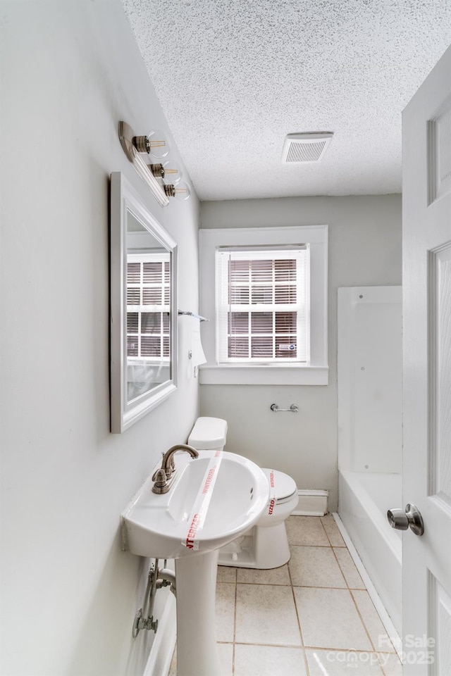 bathroom with visible vents, toilet, a bathing tub, a textured ceiling, and tile patterned flooring