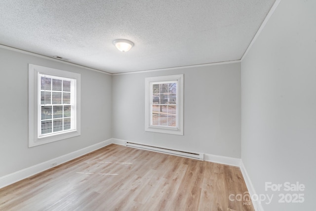 empty room with visible vents, a baseboard heating unit, baseboards, ornamental molding, and wood finished floors