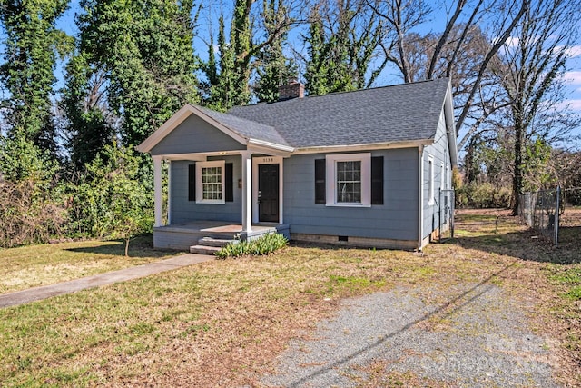 bungalow with a front lawn, a porch, fence, roof with shingles, and a chimney