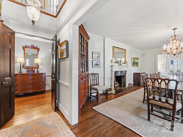 dining space featuring wood-type flooring, ornamental molding, and a notable chandelier