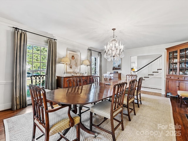 dining area with wood-type flooring, plenty of natural light, an inviting chandelier, and crown molding