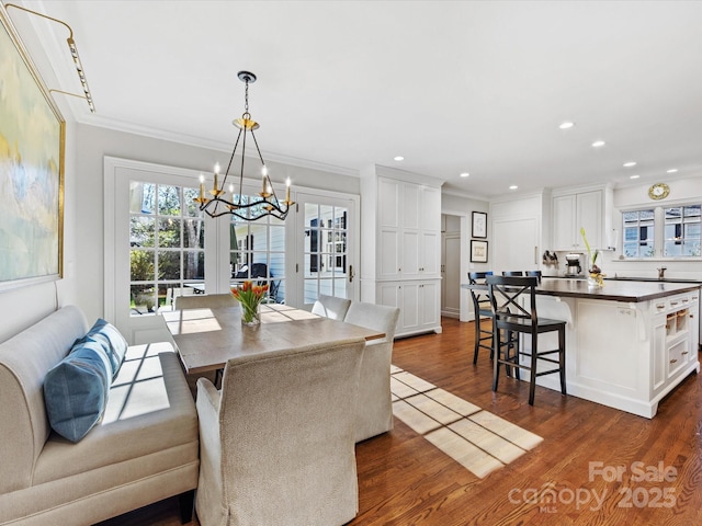 dining area featuring dark hardwood / wood-style flooring, a notable chandelier, and ornamental molding