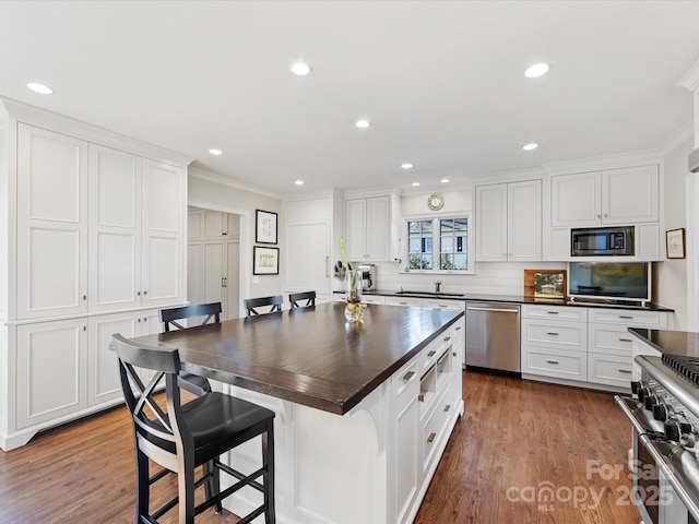 kitchen with sink, appliances with stainless steel finishes, a kitchen island, white cabinets, and a kitchen bar