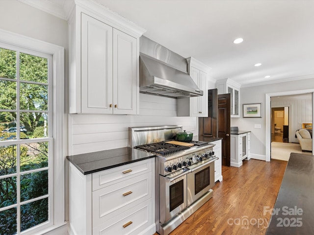 kitchen featuring dark wood-type flooring, wall chimney exhaust hood, white cabinetry, double oven range, and decorative backsplash