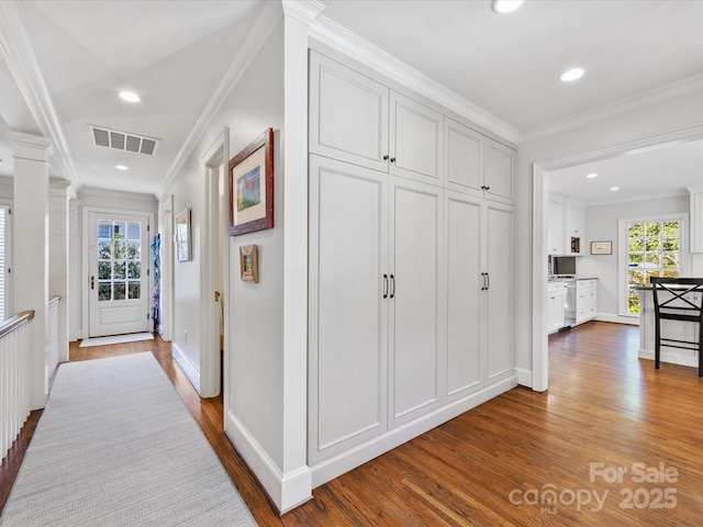 hall with plenty of natural light, ornamental molding, wood-type flooring, and ornate columns