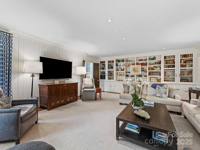 living room with built in shelves, light colored carpet, and ornamental molding