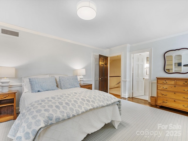 bedroom featuring hardwood / wood-style flooring, ensuite bath, and ornamental molding