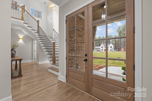 foyer entrance featuring french doors, a chandelier, and light hardwood / wood-style flooring