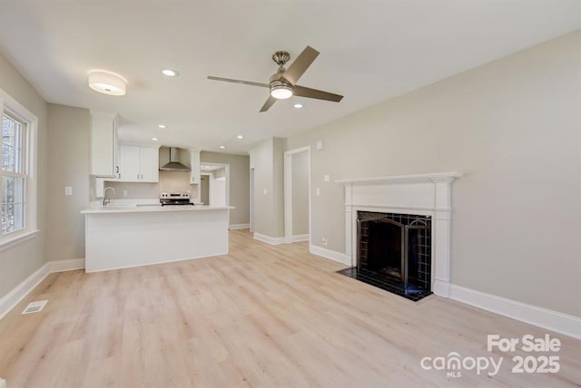 unfurnished living room with ceiling fan, sink, and light wood-type flooring