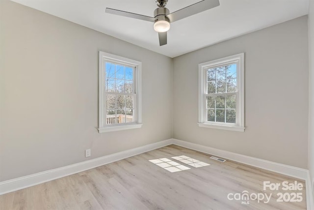 empty room with ceiling fan, a wealth of natural light, and light hardwood / wood-style floors