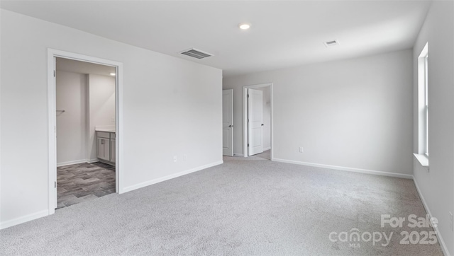 unfurnished bedroom with connected bathroom and light colored carpet