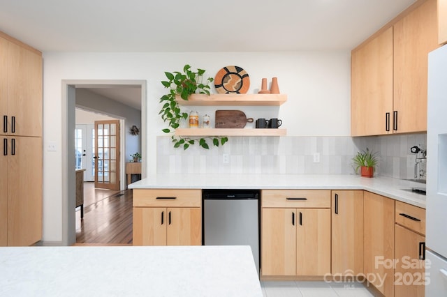 kitchen featuring stainless steel dishwasher, light brown cabinetry, and backsplash