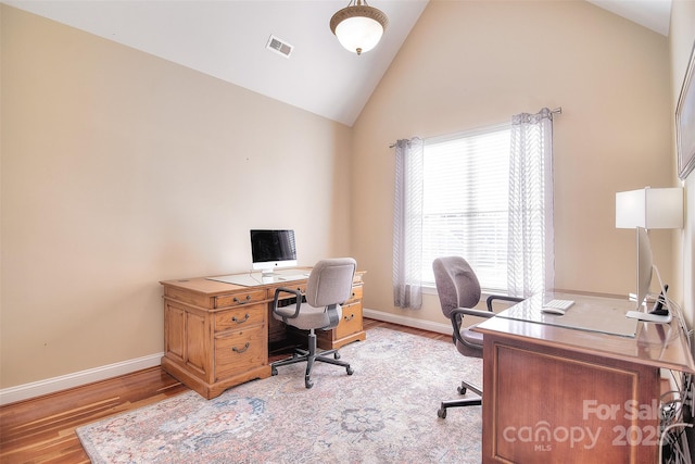 office space with high vaulted ceiling and light hardwood / wood-style flooring