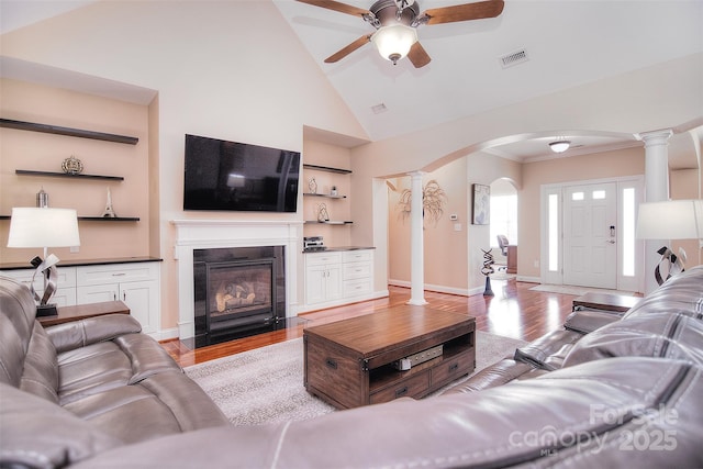 living room with ornate columns, ceiling fan, high vaulted ceiling, and light hardwood / wood-style floors