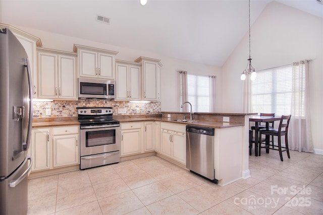 kitchen with appliances with stainless steel finishes, sink, kitchen peninsula, and cream cabinetry