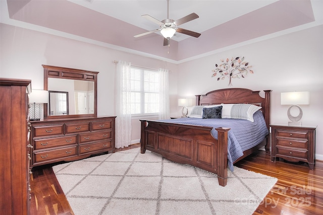 bedroom featuring hardwood / wood-style flooring, a raised ceiling, and ceiling fan