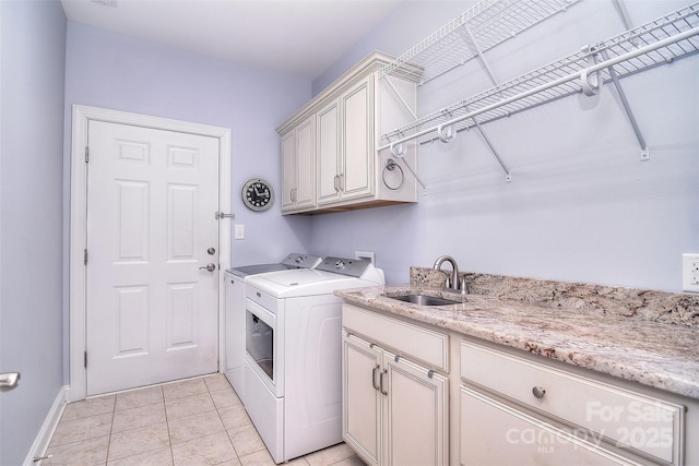 laundry room with sink, light tile patterned floors, cabinets, and independent washer and dryer