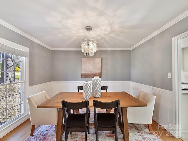 dining space with wood-type flooring, crown molding, and an inviting chandelier