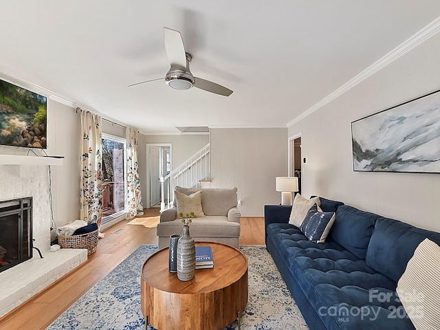 living room with crown molding, ceiling fan, a fireplace, and light hardwood / wood-style floors