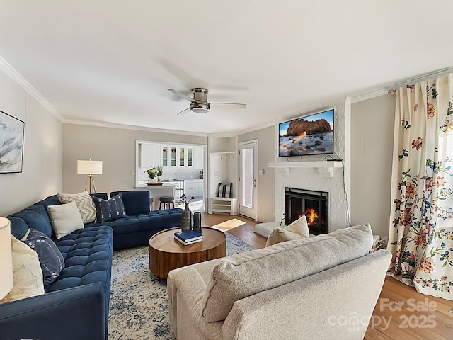 living room with a premium fireplace, crown molding, and hardwood / wood-style floors