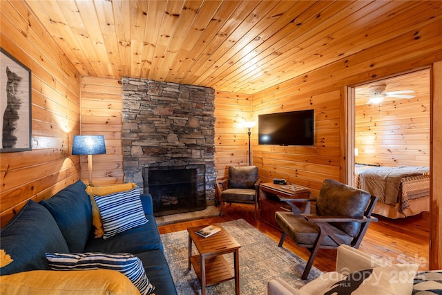 living room featuring hardwood / wood-style floors, wooden ceiling, a fireplace, and wood walls