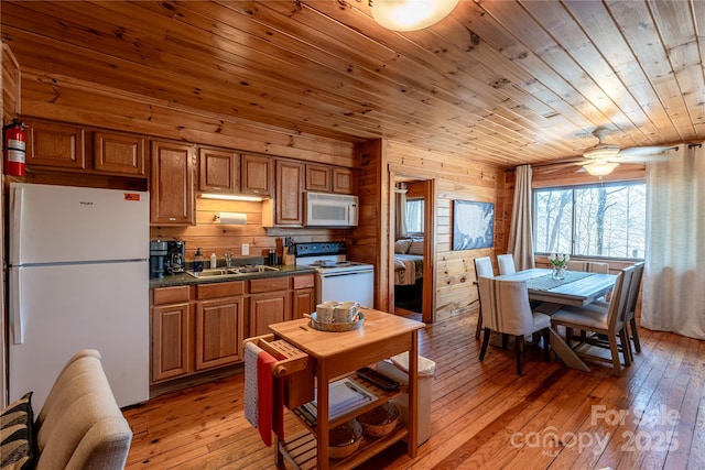 kitchen featuring sink, wooden ceiling, wooden walls, white appliances, and light hardwood / wood-style floors