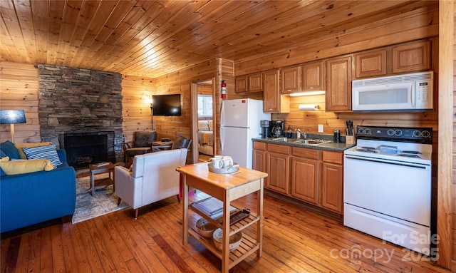 kitchen featuring sink, white appliances, wood-type flooring, and a fireplace