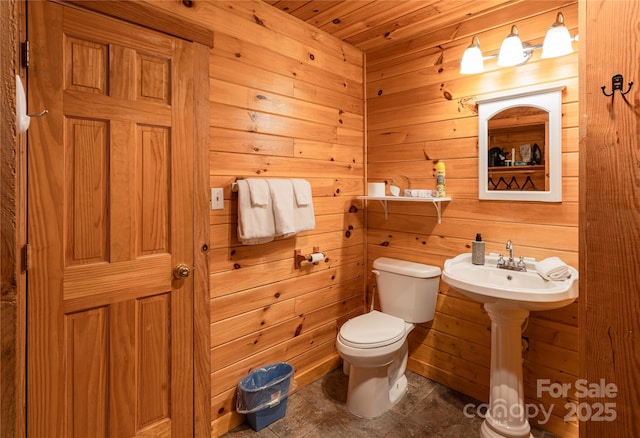 bathroom with wood walls and toilet