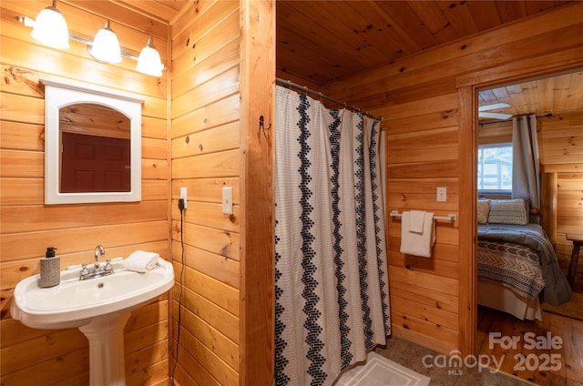 bathroom with wood ceiling, a shower with shower curtain, and wood walls