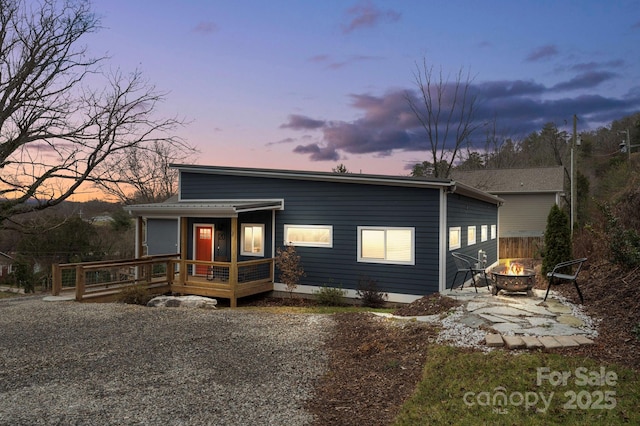 view of front facade with a wooden deck and an outdoor fire pit