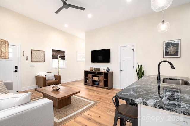 living room with sink, light hardwood / wood-style flooring, high vaulted ceiling, and ceiling fan