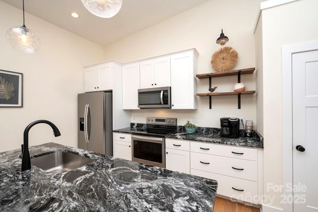 kitchen with decorative light fixtures, sink, dark stone countertops, white cabinets, and stainless steel appliances