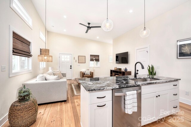 kitchen with sink, white cabinets, dark stone counters, hanging light fixtures, and stainless steel dishwasher