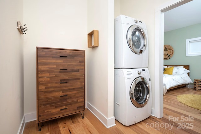 clothes washing area with light wood-type flooring and stacked washing maching and dryer
